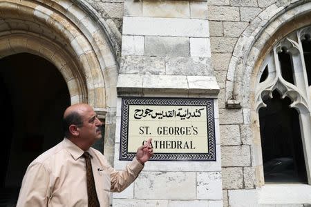 A church official gestures as he stands next to the entrance to the Anglican St. George's Cathedral in Jerusalem, June 13, 2018. Picture taken June 13, 2018. REUTERS/Ammar Awad