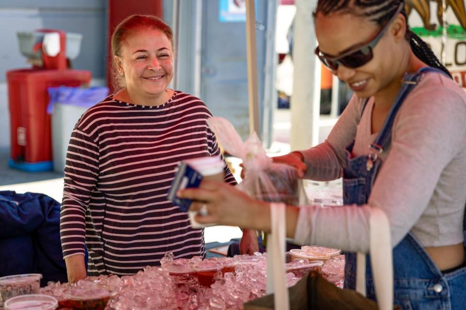 The owner of Mediterranean Pastries Den helps a customer at her booth.