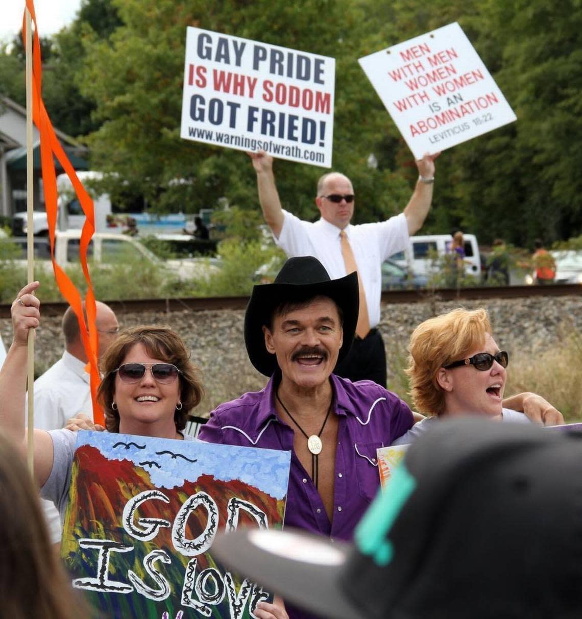 Randy Jones, the original cowboy in the pop disco group The Village People, poses for pictures in front of anti-gay preachers on Main Street in Durham in 2013.