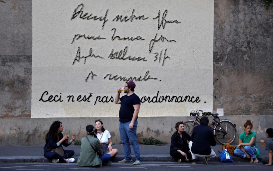 Parisians gather by an artwork that states "this is not a medical prescription" in Paris on Thursday - THOMAS COEX/AFP