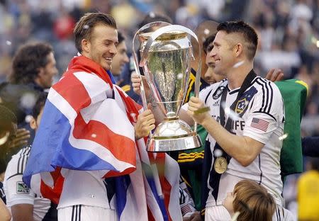 Los Angeles Galaxy's Robbie Keane (R) of Ireland hands teammate David Beckham (L) the trophy after the Galaxy defeated the Houston Dynamo to win the MLS Cup championship soccer game in Carson, California, December 1, 2012. REUTERS/Danny Moloshok