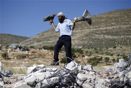 A Palestinian man holds damaged loudspeakers belonging to a mosque after it was demolished by Israeli bulldozers in Khirbet Al-Taweel village near the West Bank City of Nablus April 29, 2014. REUTERS/Mohamad Torokman