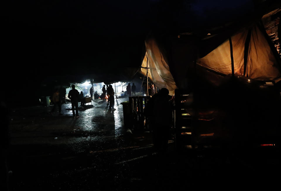 In this photo taken Wednesday, Nov. 13, 2019, migrants walk in the Vucjak refugee camp outside Bihac, northwestern Bosnia. The European Union's top migration official is warning Bosnian authorities of a likely humanitarian crisis this winter due to appalling conditions in overcrowded migrant camps in the country. (AP Photo/Darko Vojinovic)