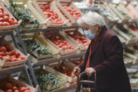 An elderly lady wearing a mask for protection against COVID-19 infection looks at vegetables after the opening of a market selling Romanian food products discounted by 25 percent for pensioners and 15 percent for students living or studying in the district surrounding,in Bucharest, Romania, Saturday, Sept. 19, 2020. Several community welfare investments were inaugurated in the recent weeks as Romania approaches the end of local elections electoral campaign, although the events were not officially related to the upcoming ballot on Sept. 27. (AP Photo/Andreea Alexandru)