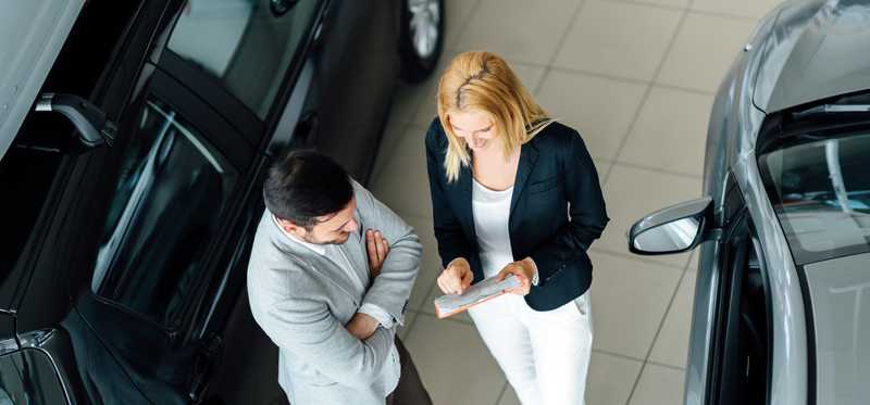 A man and a woman negotiate at a car dealer