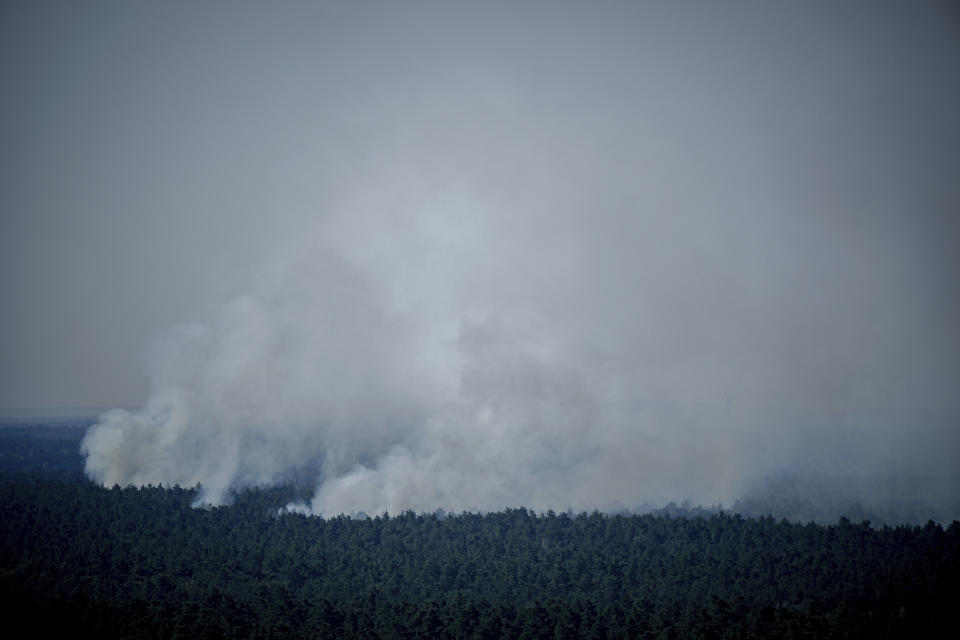 Smoke rises in Berlin's Grunewald forest in Berlin, Germany, Thursday, Aug. 4, 2022. A large fire has broke out in one of Berlin’s biggest forests triggered by several explosions that took place on a blasting site inside the forest leading to canceled public transportation and the closure of several roads. Kay Nietfeld/dpa via AP)