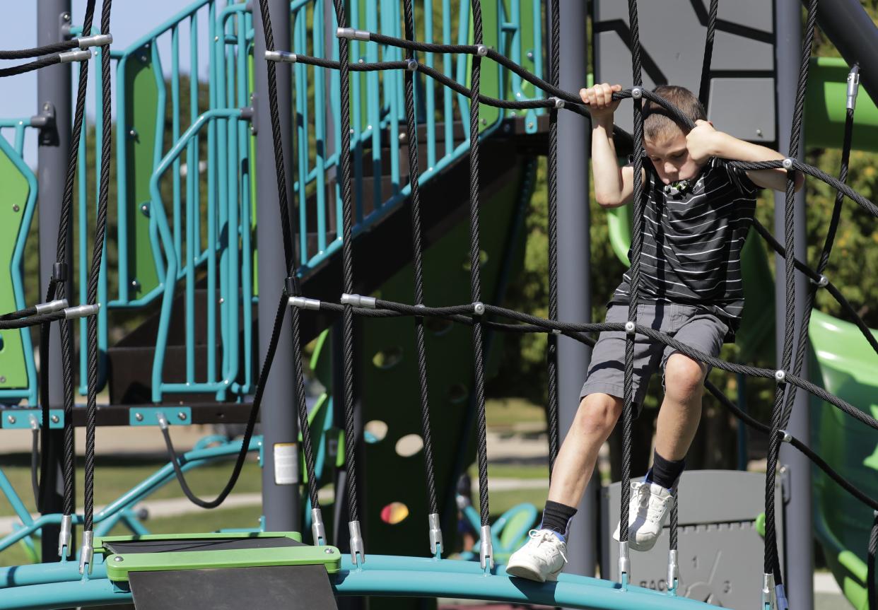 Teddy Blondheim, 10, climbs on playground equipment in August 2023, at Westhaven Circle Park in Oshkosh. Teddy has a rare genetic disorder, PIGN-CDG, that affects every aspect of his functioning including his gross motor skills and speech. He struggles on playgrounds that don't have accessible features