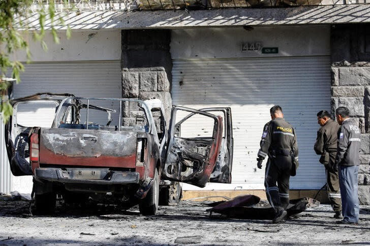 Policías revisan los restos de un automóvil, que según las autoridades estaba cargado con dos tanques de gasolina y luego explotó cuando los sospechosos le prendieron fuego, aparentemente apuntando a la agencia penitenciaria de Ecuador SNAI, en Quito, Ecuador