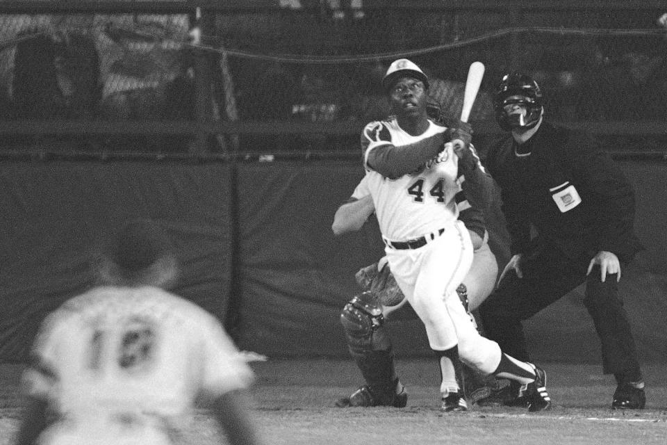FILE - Atlanta Braves' Hank Aaron eyes the flight of the ball after hitting his 715th career homer in a game against the Los Angeles Dodgers in Atlanta, Ga., in this April 8, 1974 file photo. Dodgers pitcher Al Downing, catcher Joe Ferguson and umpire David Davidson look on. Hank Aaron, who endured racist threats with stoic dignity during his pursuit of Babe Ruth but went on to break the career home run record in the pre-steroids era, died early Friday, Jan. 22, 2021. He was 86. The Atlanta Braves said Aaron died peacefully in his sleep. No cause of death was given. (AP Photo/Harry Harrris, FIle) ORG XMIT: NY156