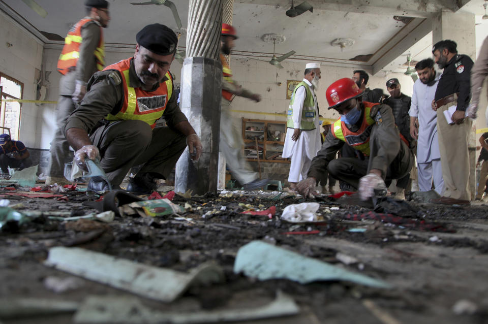 Pakistani rescue workers and police officers examine the site of a bomb explosion in an Islamic seminary, in Peshawar, Pakistan, Tuesday, Oct. 27, 2020. A powerful bomb blast ripped through the Islamic seminary on the outskirts of the northwest Pakistani city of Peshawar on Tuesday morning, killing some students and wounding dozens others, police and a hospital spokesman said. (AP Photo/Muhammad Sajjad)