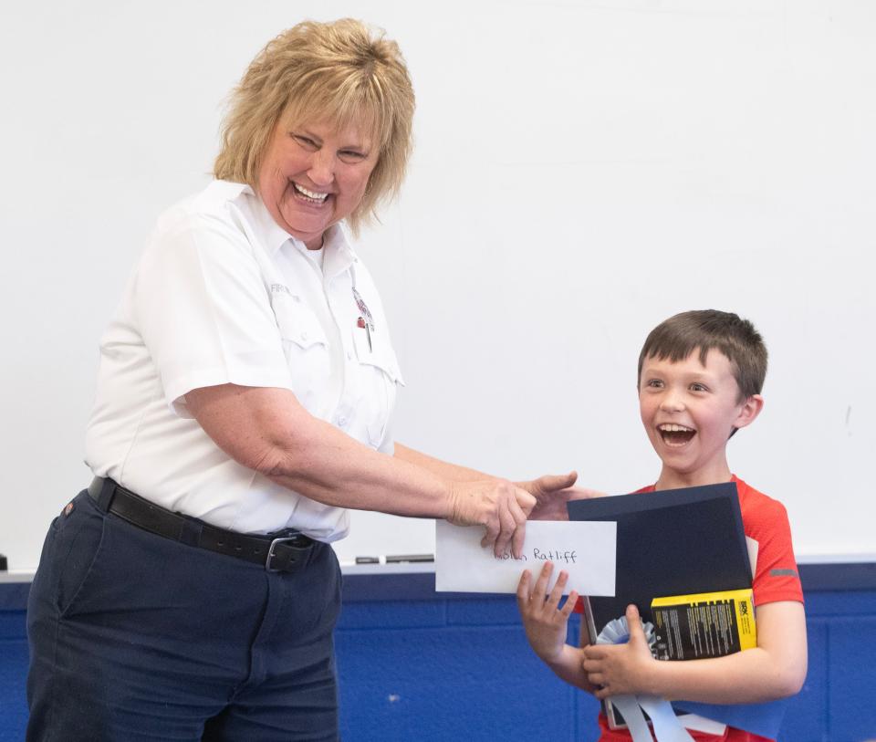 Nolan Ratliff, 9, is all smiles after he was awarded "V-Bucks" for the video game Fortnite by Massillon Fire Inspector Tammy Wagner for his first-place win in the state Fire Marshal's fire safety poster contest. The Tuslaw third grader was selected as the top creator from 150 other posters submitted by students from across the state.