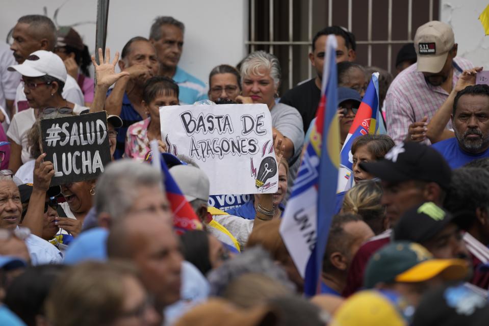 A supporter holds a handmade sign with a message that reads in Spanish: "Enough with the blackouts", at the campaign launch of Venezuelan presidential candidate Edmundo González Urrutia, in La Victoria, Venezuela, Saturday, May 18, 2024. (AP Photo/Ariana Cubillos)