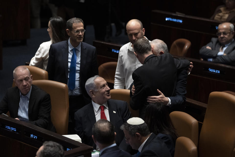 Israel's Prime Minister Benjamin Netanyahu, center, and lawmakers congratulate Justice Minister Yariv Levin, back to camera, after his speech in Israel's parliament, the Knesset, just before a vote on a contentious plan to overhaul the country's legal system, in Jerusalem, early Tuesday, Feb. 21, 2023. (AP Photo/Maya Alleruzzo, Pool)