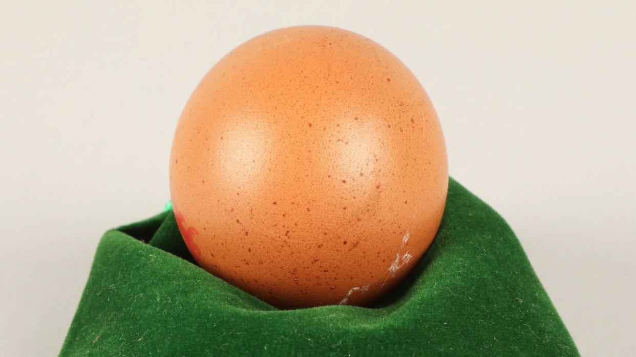 Round-shaped chicken egg displayed on a green cloth.