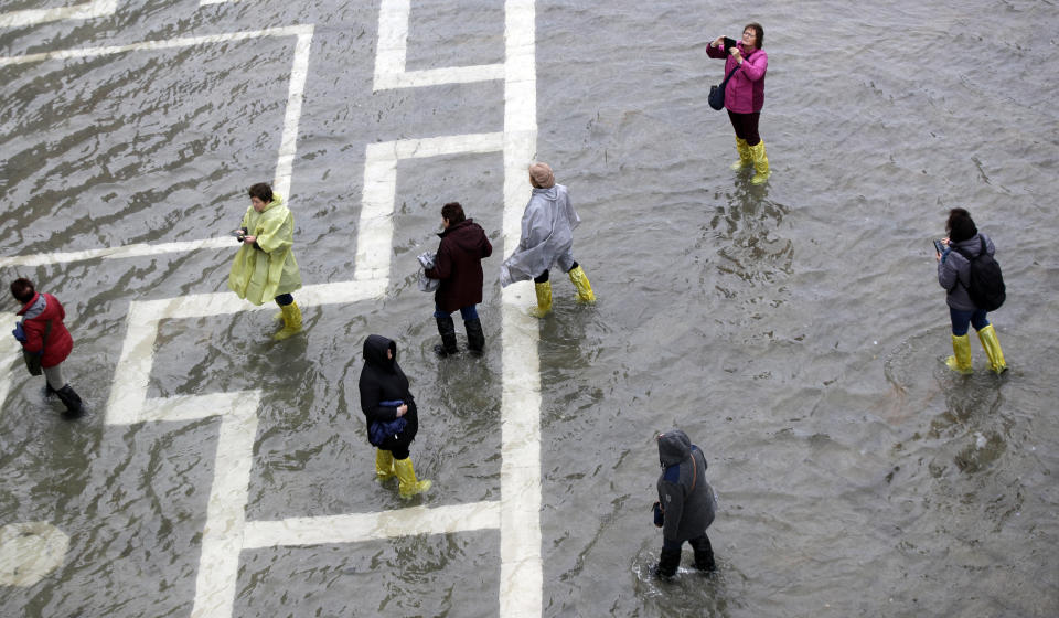 People walk in a flooded St. Mark's Square, in Venice, Italy, Tuesday, Nov. 12, 2019. (Photo: Luca Bruno/AP)