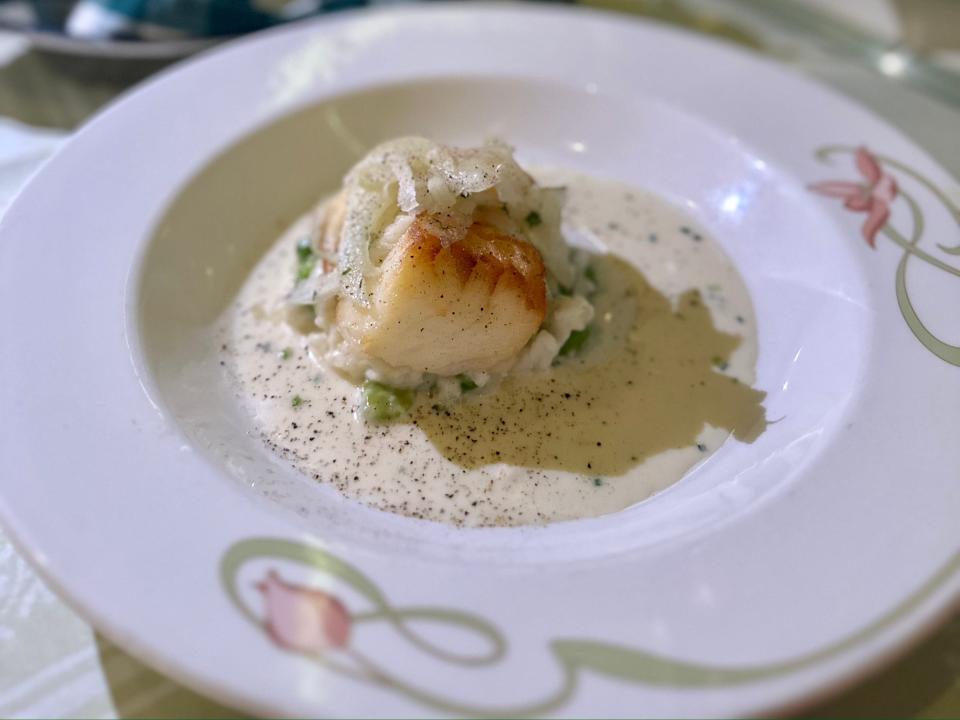 Sea bass on a plate with a white sauce.