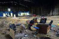 Migrants sit in an abandoned factory outside Velika Kladusa, Bosnia, Saturday, Sept. 26, 2020. Remote woods, abandoned run-down buildings and roadsides on the fringes of northwestern Bosnian towns are steadily filling with makeshift camps where migrants from the Middle East, Asia and North Africa are bracing for more misery as autumn's chill and rains set it. (AP Photo/Kemal Softic)