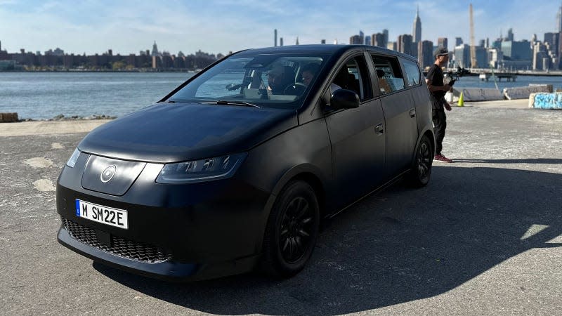 A photo of the Sion electric car with the New York skyline behind. 