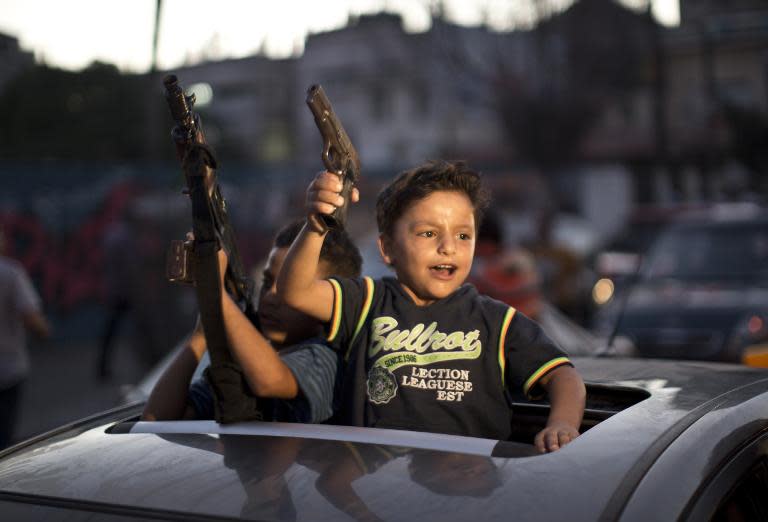 Un par de niños sostienen armas desde un coche durante las celebraciones por el alto el fuego entre Hamas e Israel en la Franja de Gaza, el 26 de agosto de 2014