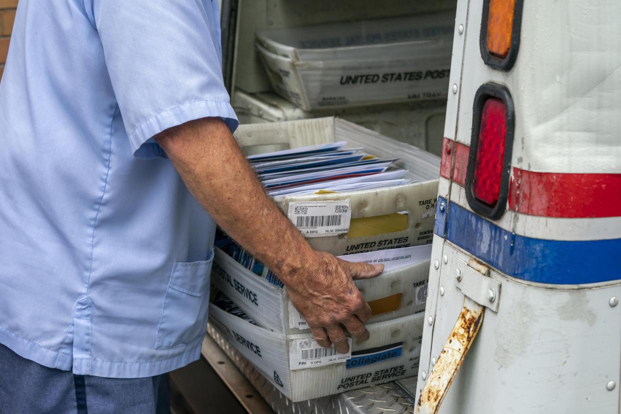 Mail carriers load trucks for deliveries at a U.S. Postal Service facility.