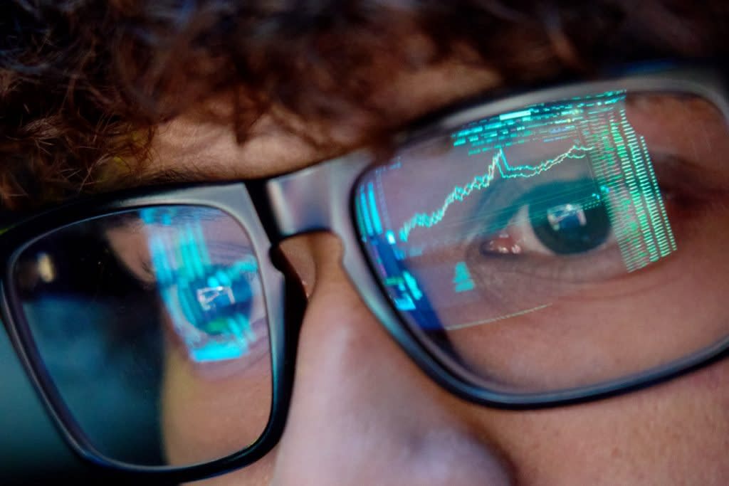 The stock market is reflected in a person's glasses. 