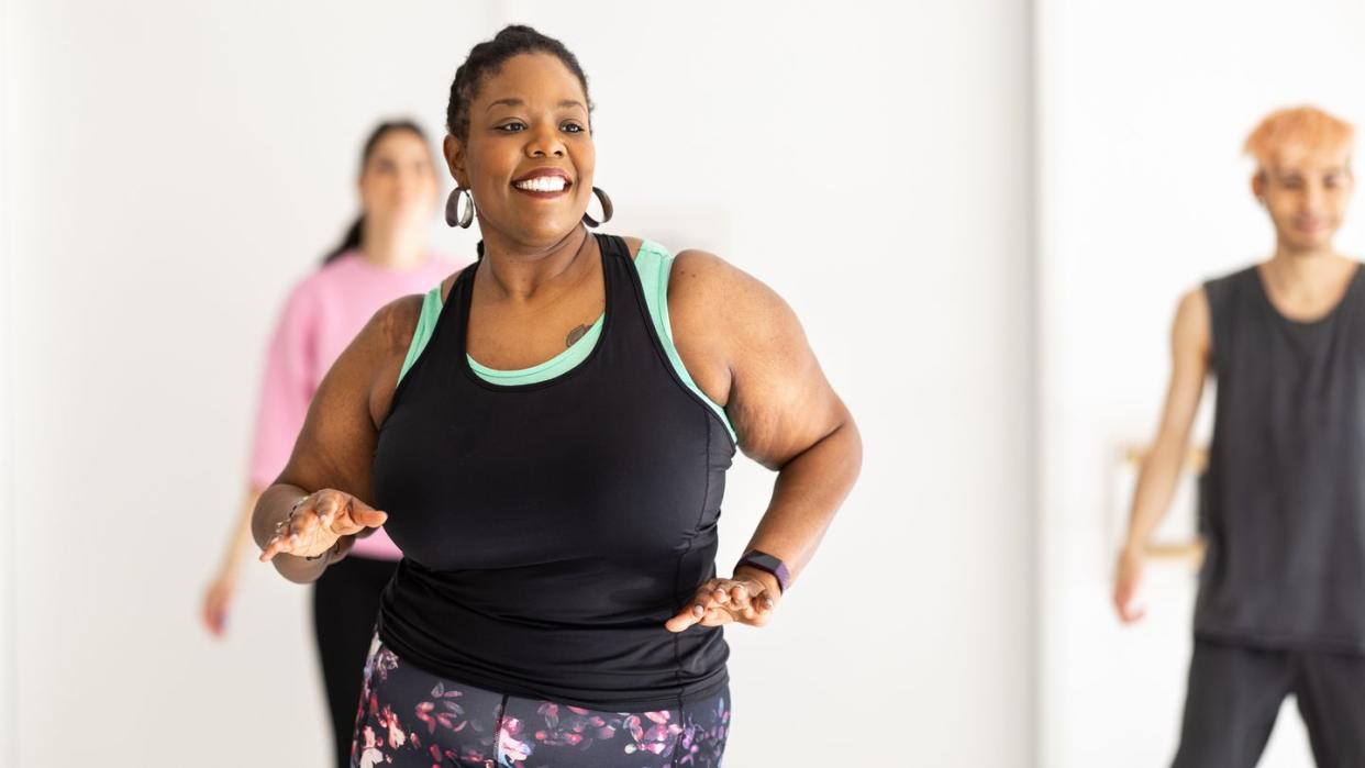 smiling african woman enjoying dancing at fitness studio