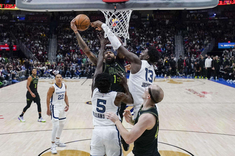 New Orleans Pelicans forward Brandon Ingram goes to the basket between Memphis Grizzlies guard Vince Williams Jr. (5) and forward Jaren Jackson Jr. (13) in the first half of an NBA basketball game in New Orleans, Tuesday, Dec. 19, 2023. (AP Photo/Gerald Herbert)