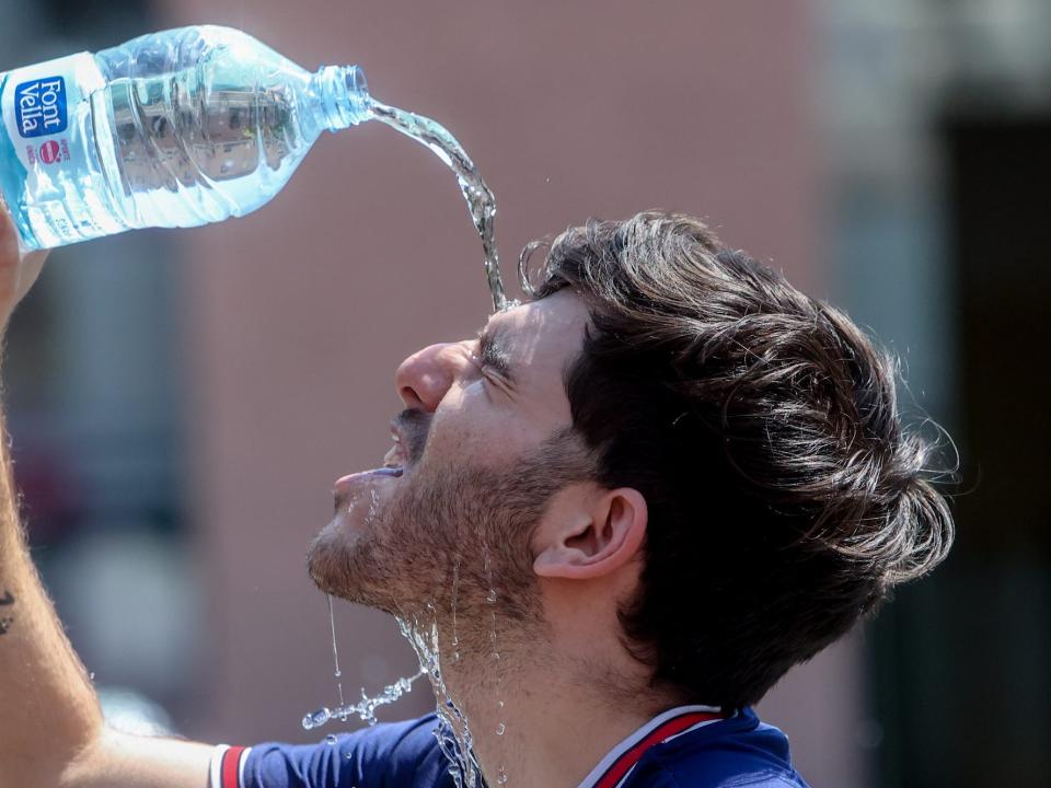 A man drops water on his forehead from a plastic bottle.