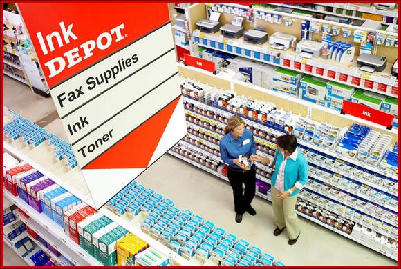 An overhead view of an employee and a customer talking in the Office Depot ink section.