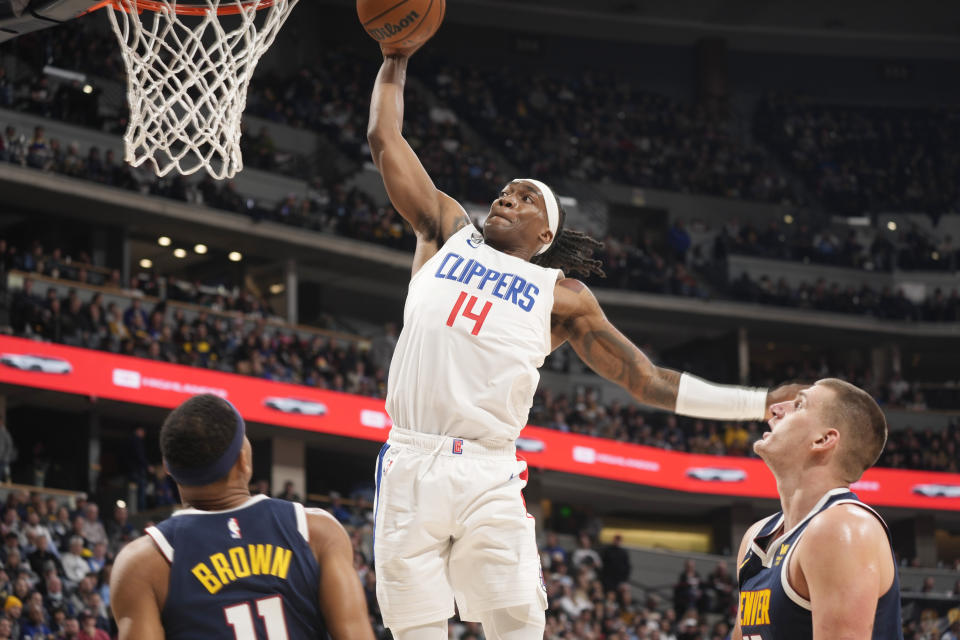 Los Angeles Clippers guard Terance Mann dunks between Denver Nuggets forward Bruce Brown, left, and center Nikola Jokic during the second half of an NBA basketball game Thursday, Jan. 5, 2023, in Denver. (AP Photo/David Zalubowski)