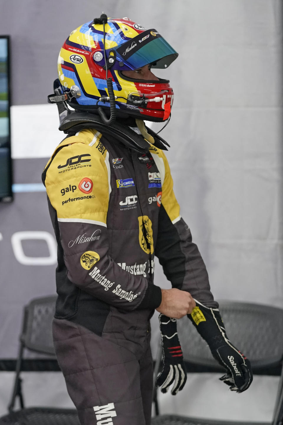 Loic Duval, of France, puts on his gloves before taking a turn driving during a practice session for the Rolex 24 hour auto race at Daytona International Speedway, Friday, Jan. 28, 2022, in Daytona Beach, Fla. (AP Photo/John Raoux)