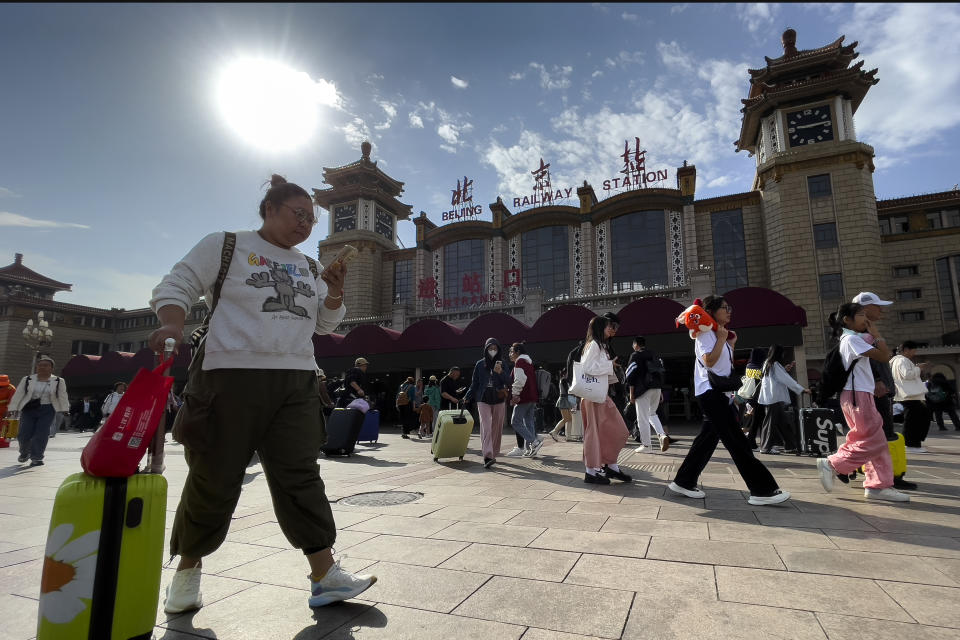 Travelers walk by the main entrance of Beijing Railway Station in Beijing, Friday, Sept. 29, 2023. Tens of millions of Chinese tourists are expected to travel within their country, splurging on hotels, tours, attractions and meals in a boost to the economy during the 8-day autumn holiday period that began Friday. (AP Photo/Andy Wong)