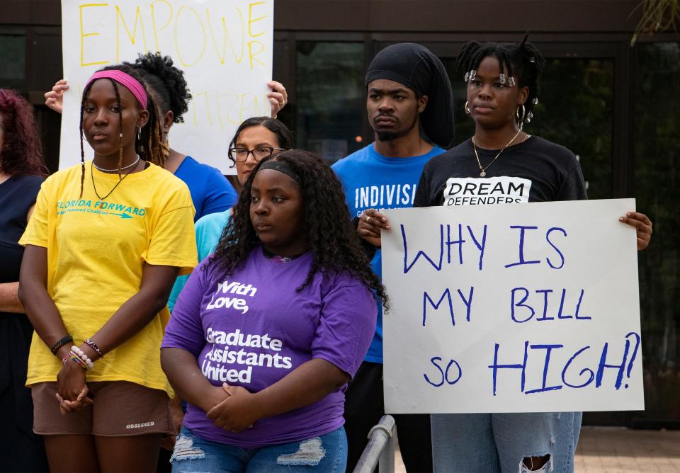 Attendees holds signs during a press conference hosted by Community Leaders United at the Gainesville Regional Utilities building downtown on Aug. 25.