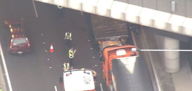 Driver escapes after car becomes wedged between two trucks in the Burnley Tunnel. Photo: 7News