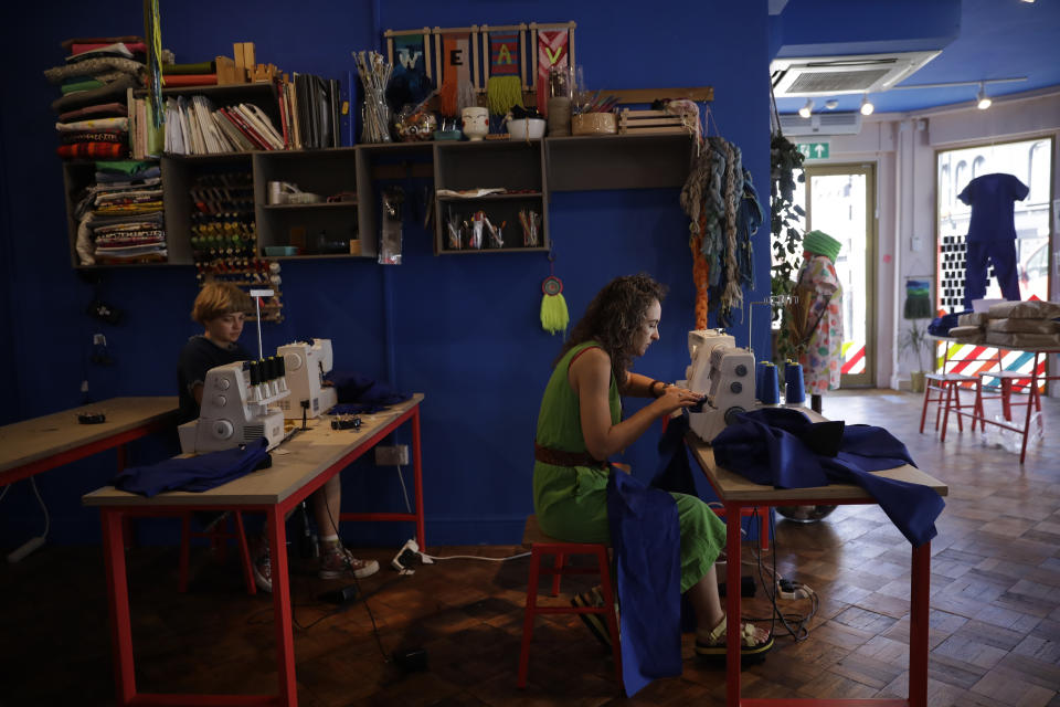 Textile artist Brooke Dennis, right, who is originally from New Zealand, makes scrubs for NHS (National Health Service) staff to wear during the coronavirus outbreak, at her textiles and craft studio called Make Town, in east London, Thursday, April 23, 2020, as part of the Scrub Hub network of voluntary community groups. The Scrub Hub just wanted to help, but they created a movement of volunteers responding to the coronavirus pandemic that has so far churned out more than 3,800 sets of scrubs for healthcare workers. (AP Photo/Matt Dunham)