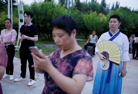 A man dressed in "Hanfu" stands next to residents at an event held to mark the traditional Qixi festival, at a park in Beijing, China