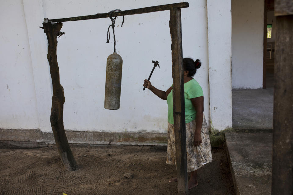 In this Feb. 11, 2018 photo, Elvira Mendoza Espinosa, hits a diving tank with a hammer announcing the start of the morning Mass, outside the Moravian church in Kaukira, Honduras. In the Mosquitia, diving permeates everyday life, as it does in Kaukira, one of the villages on the Mosquitia. (AP Photo/Rodrigo Abd)