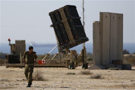 An Israeli soldier walks in front of an Iron Dome missile interceptor battery deployed in the southern Israeli coastal city of Ashkelon October 28, 2013. REUTERS/Amir Cohen