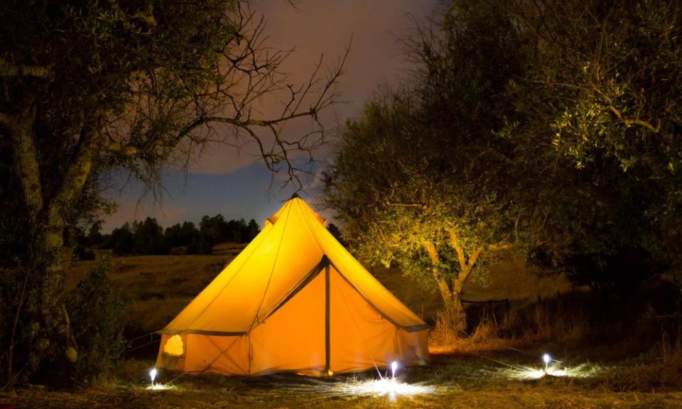 lit tent under trees in dark