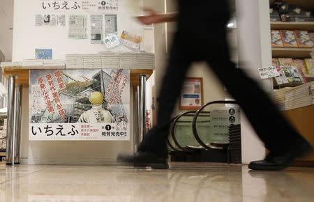 A staff walks past a poster of a Japanese Manga "Ichi Efu", which centres on workers at the Fukushima Daiichi nuclear plant, at a bookstore in Tokyo June 23, 2014. REUTERS/Yuya Shino
