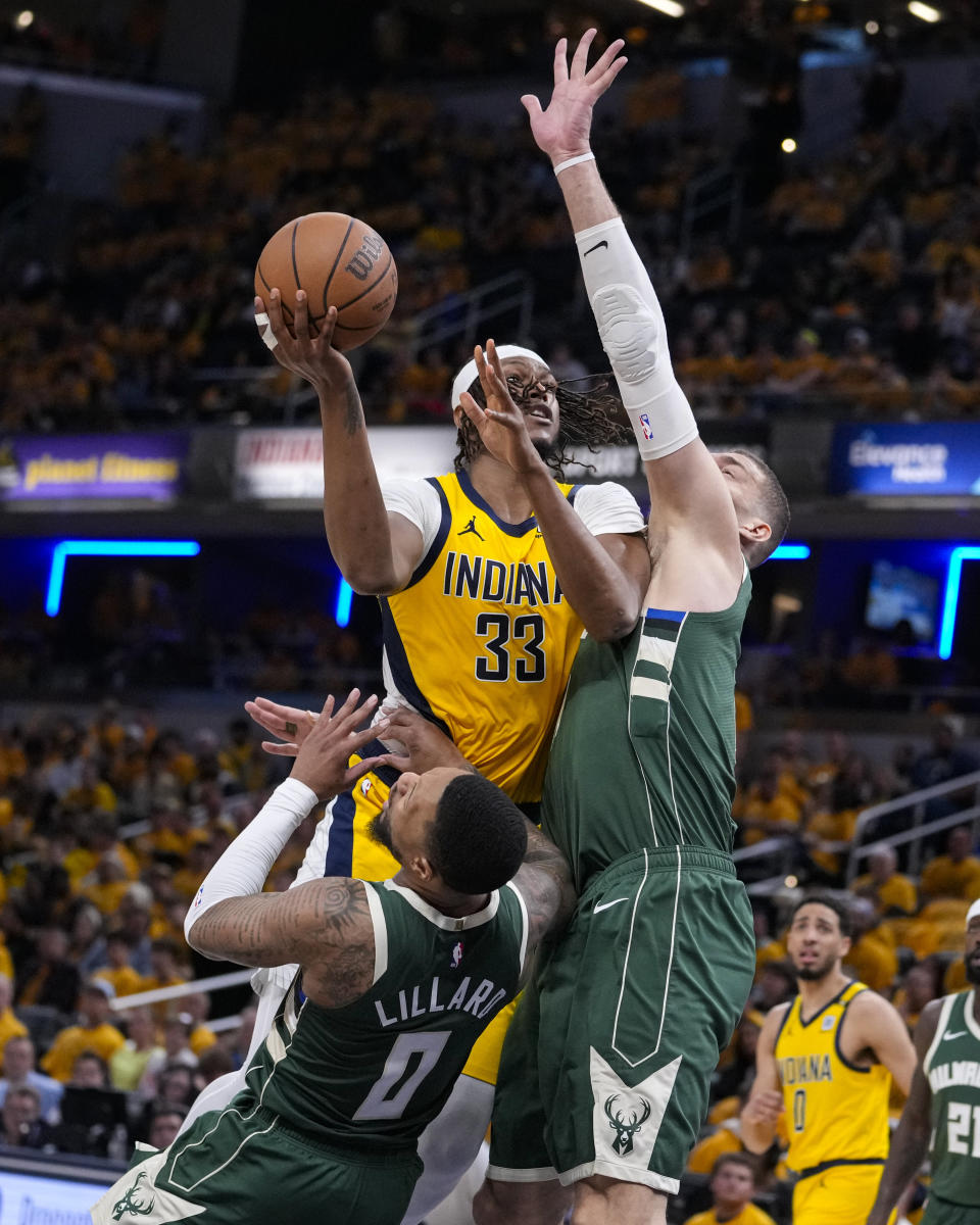Indiana Pacers center Myles Turner (33) is fouled as he shoots over Milwaukee Bucks guard Damian Lillard (0) and center Brook Lopez (11) during the second half in Game 2 in an NBA basketball first-round playoff series, Friday, April 26, 2024, in Indianapolis. (AP Photo/Michael Conroy)