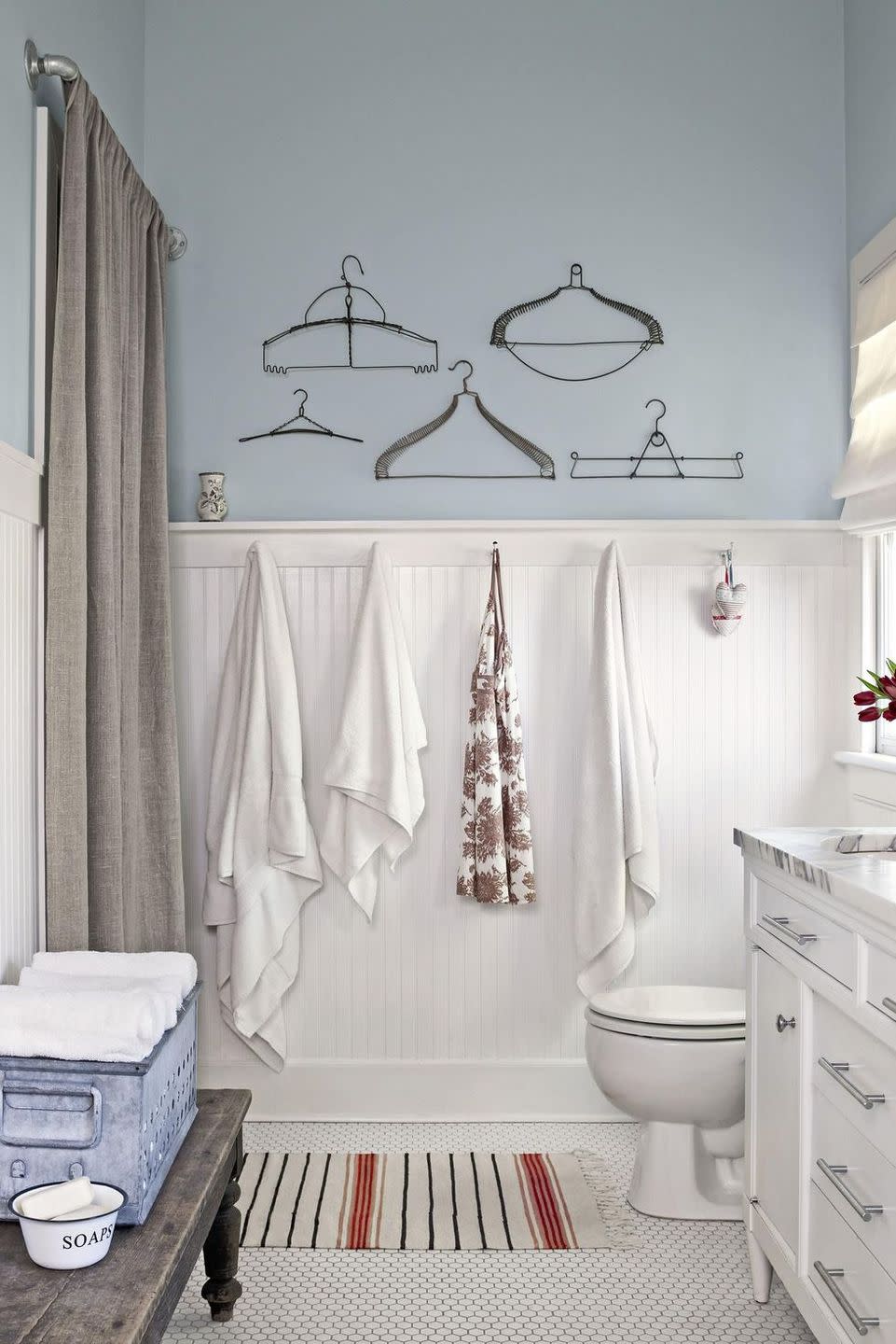 bathroom floor tiled with small white hex tiles, with white beadboard wainscoting and pale blue upper walls