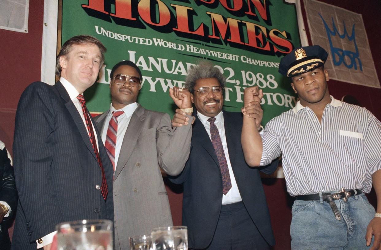 Boxing Promoter Don King, second from right, holds the wrists of the undisputed world heavyweight champion Mike Tyson, right, and his challenger Larry Holms as entrepreneur Donald Trump looks on in New York on Dec. 1, 1987.