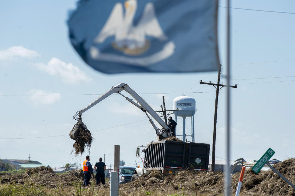 Terrebonne Parish solid waste crews remove marsh grass that washed across La. 56 in Cocodrie, La., during Hurricane Zeta, as residents slowly return to their homes and fishing camps to assess the damage on Thursday, October 29, 2020. (Chris Granger/The Advocate via AP)