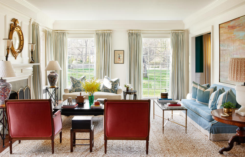 In the living room of a historic home in Cold Spring Harbor, New York, A.A. Baker Design mixed custom and vintage upholstery with antique and vintage tables, including a marble and brass coffee table from Antique & Artisan. The firm balances the formality of the room with a jute rug.