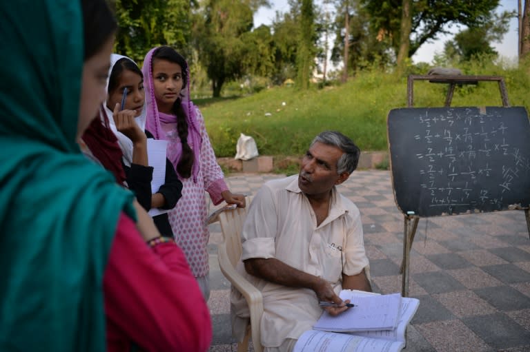 Muhammad Ayub (R) has a day job that includes defusing bombs and putting out fires and teaches slum children for free