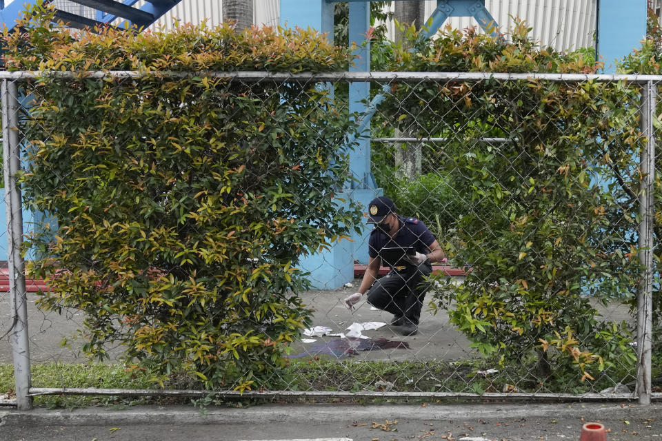 A police investigator checks the crime scene at the Ateneo de Manila University in Quezon city, Philippines, Sunday, July 24, 2022. At least three people, including a former Philippine town mayor, were killed and another was wounded in a brazen attack on Sunday by a gunman in a university campus in the capital region, officials said. (AP Photo/Aaron Favila)