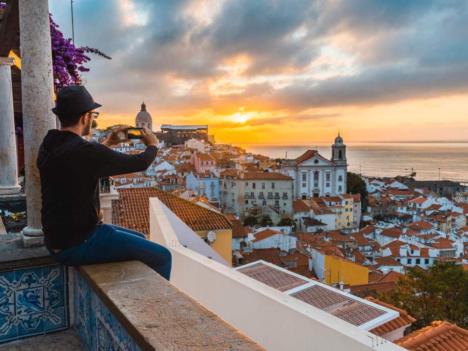 A tourist photographs the sunrise in Lisbon, Portugal, ranked as the top city in the world for remote workers.