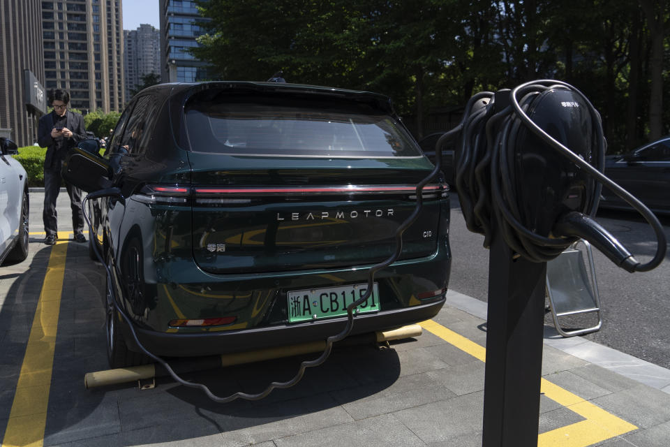 A man stands near a Leapmotor vehicle being charged outside a showroom in Hangzhou in eastern China's Zhejiang province on Tuesday, May 14, 2024. European carmaker Stellantis on Tuesday said it had formed a joint venture with the Chinese electric vehicle startup Leapmotor that will begin selling EVs in nine European countries later this year. (AP Photo/Caroline Chen)