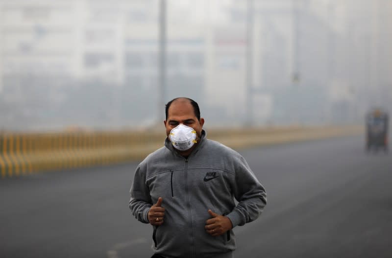 A man wearing a protective mask jogs on a foggy morning in Noida on the outskirts of New Delhi